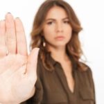 Woman with raised hand signaling a stop against a blurred background, related to plumbing issues during heavy rains.