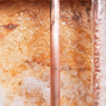 Copper pipes with crystalline formations showcasing texture and warm colors, emphasizing plumbing for winter protection.