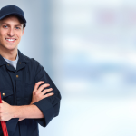 Smiling plumber in work attire holding a wrench, set against a neutral workshop background for B & D Plumbing, Heating & A/C.