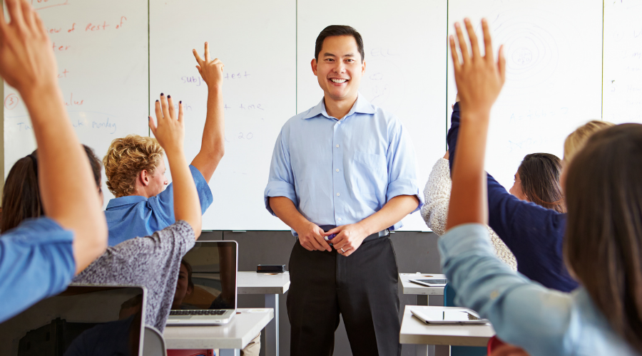 Male teacher in a classroom with engaged students, emphasizing modern education tools and interactive learning.
