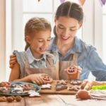 Mother and daughter baking decorated cookies on a wooden table, celebrating fall with B & D home activity tips.