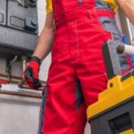 Person in red overalls and gloves in an industrial setting, showcasing HVAC work for B & D Plumbing, Heating & A/C.