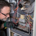 Technician repairing a furnace, focused on detailed internal wiring at B & D Plumbing, Heating & A/C.