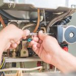 Technician repairing heating system with tools for B & D Plumbing, Heating & A/C.