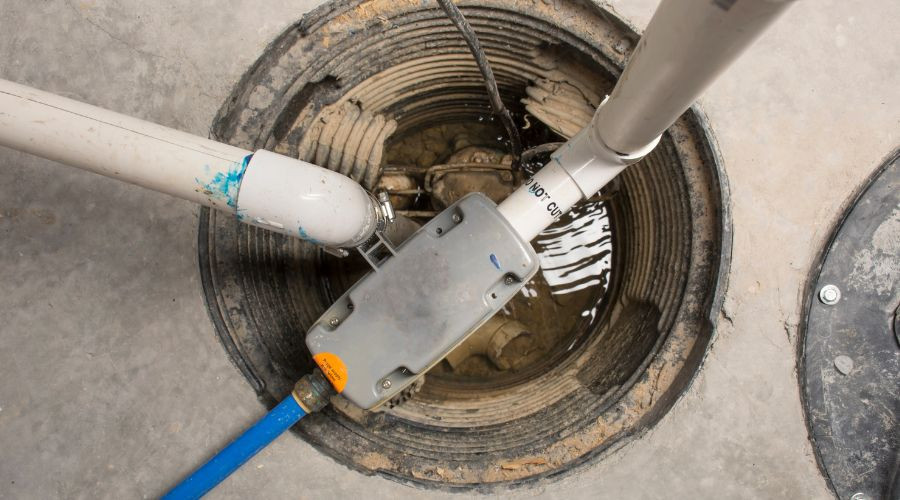 Sump pump with drainage pipes in a circular pit, featuring water accumulation and electrical connection, by B & D Plumbing.