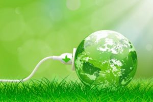 Green globe with a plug, symbolizing energy efficiency and environmental sustainability, set against a grassy background, reflecting benefits of modern boilers in reducing carbon emissions and enhancing indoor air quality.