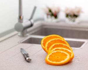Sliced oranges on a kitchen countertop with a knife, emphasizing the use of citrus for cleaning garbage disposals.