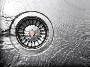 Garbage disposal unit with water flowing, illustrating routine maintenance for kitchen waste management and odor elimination.